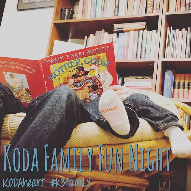 [Image Description: "KODA Family Fun Night" is written in a dark teal color in the very bottom of the photo. The photograph is of a adult and child's legs sitting in a large bowl like wood chair. They are reading "Mary Engelbreit's Mother Goose". Behind them sits a full bookshelf. "KODAheart #k3family" in a dark teal color underneath "KODA Family Fun Night" in the bottom left corner.]