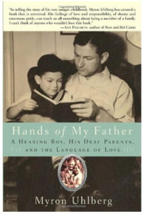 Image Description: The title is in light teal banner placed just below the center of the book “Hands of My Father”. Behind this banner is a photo in a sepia tone of a man with a child in their lap looking at a book. Above the photo is a review, below the title is a picture of a photo of a couple with a silver border. 