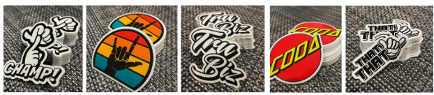 [Image Description: 5 thumbnail photos of deaf culture related stickers. The first is a black and white sticker with the ASL sign for champ on top of the English word Champ with an exclamation point. The second is a black ILY handshape on a colorful striped background. The third photo is a black and white of the phrase Tru Biz. The next photo is a sticker that has the word CODA in yellow on a red background. The final sticker is a black and white of the “That” handshape next to the word THAT.] 