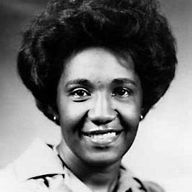 Image Description: a black and white portrait of an African American woman in 1970's attire. She is smiling at the camera.