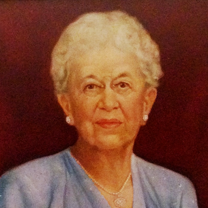 Image description: This painted portrait shows Elizabeth Peet seated with her hands clasped in her lap. She is wearing a belted blue dress and a long necklace. Her white hair is pulled back and she looks out from the painting with a calm smile.