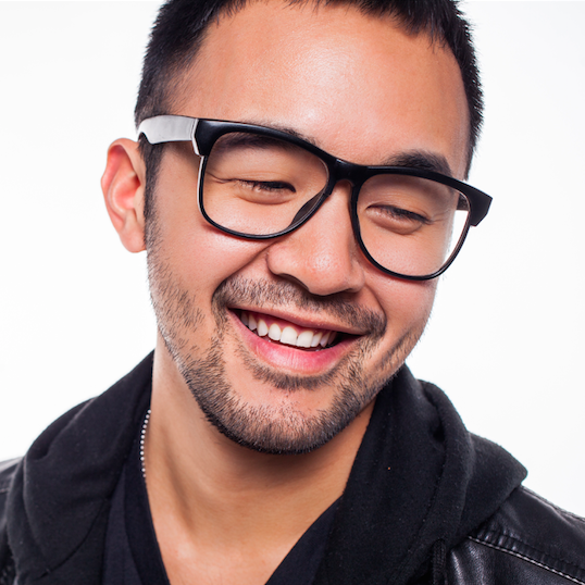 Image description: a Taiwanese man, smiling, with black rimmed glasses looking to the lower right wearing a leather jacket.