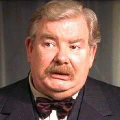 Image Description: A movie still of Richard Griffiths shows a white man with greying hair and a mustache wearing a suit jacket and bow tie. He is looking to the left with a concerned expression on his face.